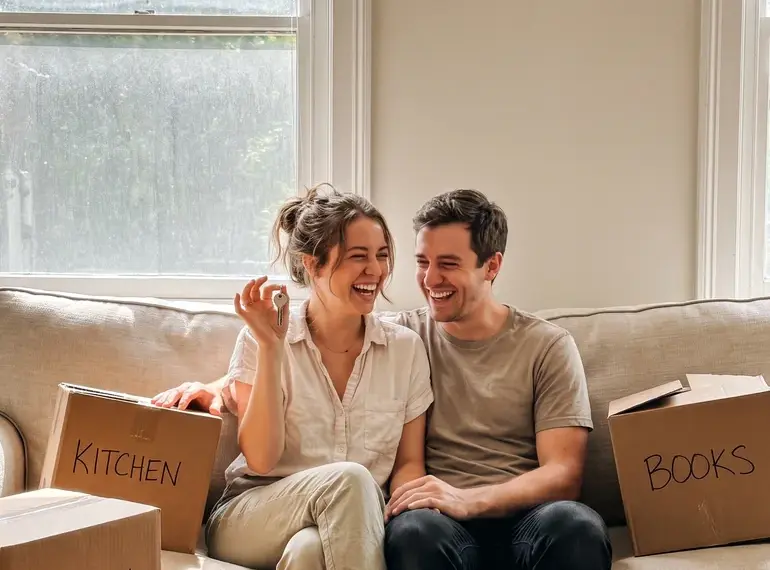 Happy couple with keys among moving boxes in their new Orlando home